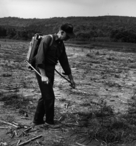 Keith Arnold with a backpack tool on his back in the forest