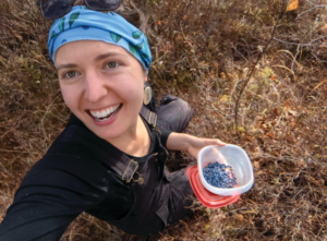 Kelsey Aho outside holding a blueberries