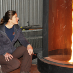 Dr. McAllister kneels next to a tall cylinder containing a column of fire.