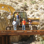 Michael Balen and his coworkers standing around an excavator in a rocky area