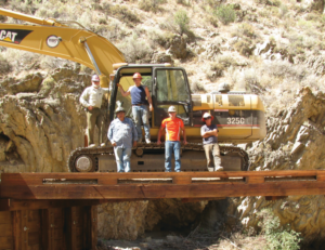 Michael Balen and his coworkers standing around an excavator in a rocky area