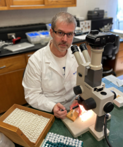 Dr. Havill works in his lab in front of a microscope.