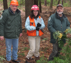Dr. Munck (middle) stands between two other people in a forest.