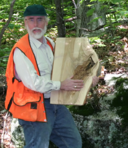 Dr. Smith holds a cross-section of a tree trunk.