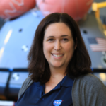Ms. Jones stands in front of a crew module in a NASA facility