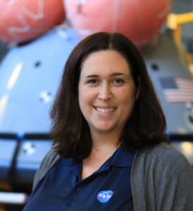 Ms. Jones stands in front of a crew module in a NASA facility