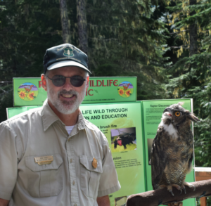 Ron Kikel outside next to an owl on a limb