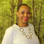 Dr. Parker smiles at the camera in front of a backdrop of trees