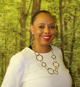 Dr. Parker smiles at the camera in front of a backdrop of trees