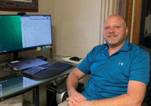 Mr. Lacina sits in front of his desktop computer.