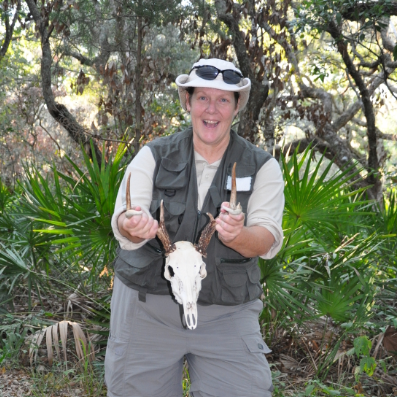 Susan Best in an outside area holding up an animal skull