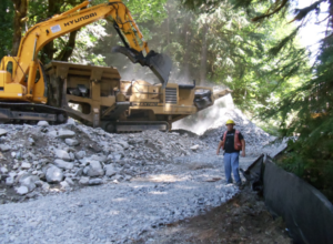 Todd Griffin with a large bulldozer behind him in a natural area