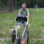 Velicia Berstrom pushing a instrument through a grassy area