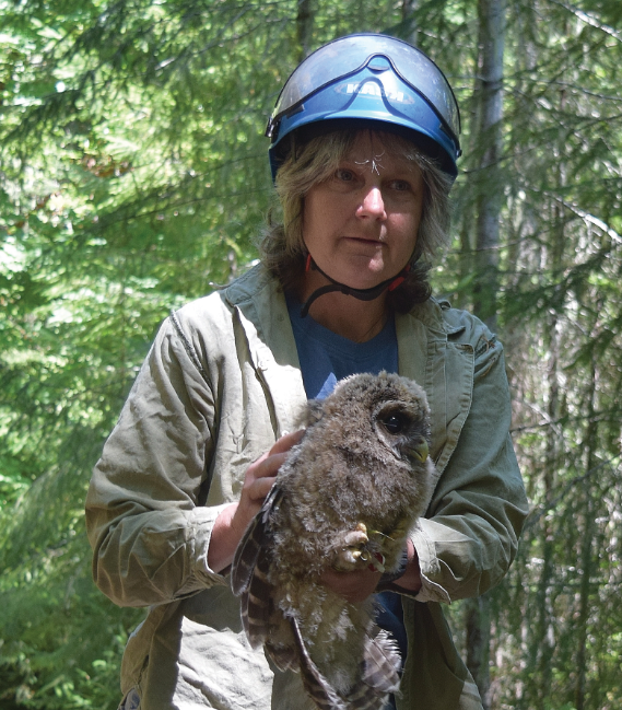 Ms. Reid holds an owl in a forest