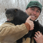 Dr. Malcolm holds a wolverine in the snow.