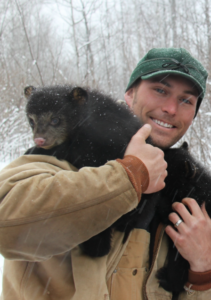 Dr. Malcolm holds a wolverine in the snow.
