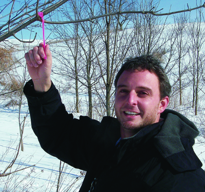 Dr. Widenhoeft holds a tag on a tree branch