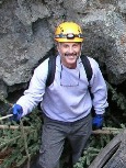 Bradley Phillips in a hard hat standing infront of a cave